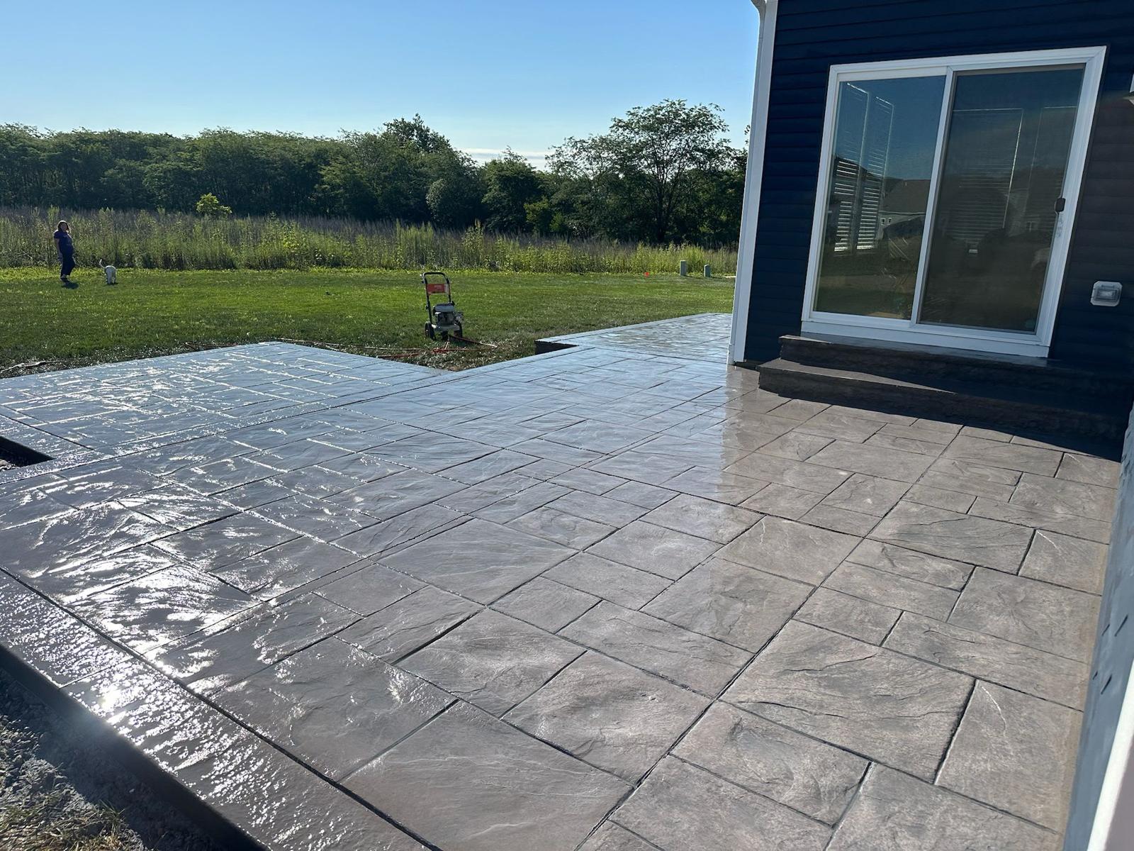 High-gloss sealed stamped slate patio reflecting sunlight with rich slate texture